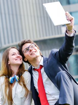 Young Business couple making selfie photo with tablet and buildings on background