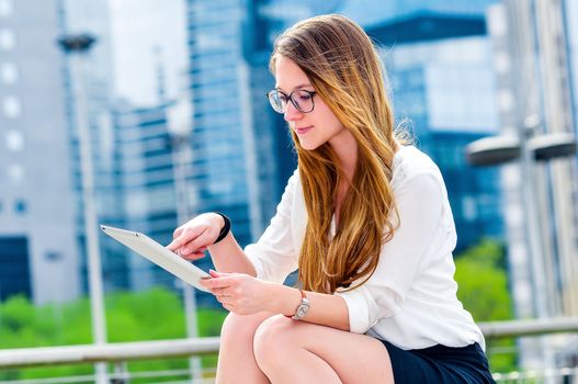 dynamic young executive girl working outside n a touchscreen tablet. Free of any constraint. Symbol of a job search or trade of outsourcing