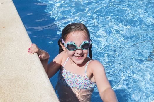 Smiling girl enjoying the pool in summer