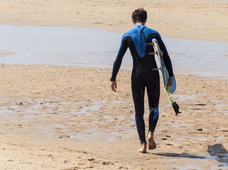 Surfer walking into the warter on the sun at the beach