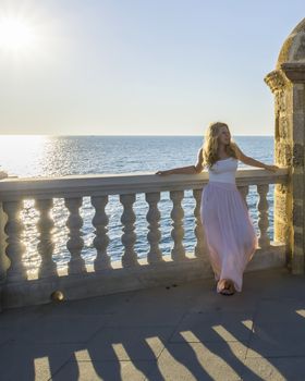 Young woman posing on a balcony facing the sea