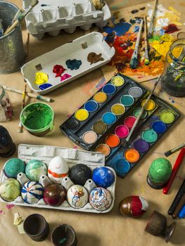 Photo of a messy table filled with egg decorating materials for making Easter eggs.