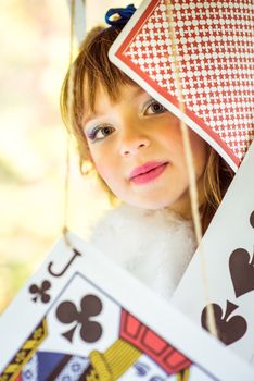 Portrait of little beautiful girl in the scenery of Alice in Wonderland with big game cards