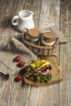 Sandwich with vegatables and tomatoes on an old wooden table
