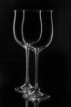 Two empty glasses on a black studio glass background