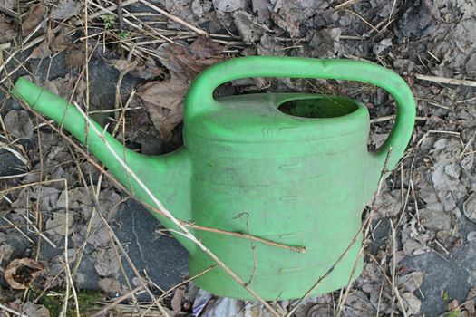 green plastic watering can an abandoned garden still life