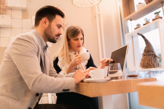 Two young businesspeople working on laptop on a break at cafe.