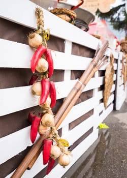 Garlic and hot chili peppers hanging on  white wooden background outdoor.