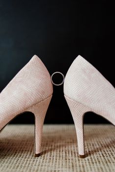 Wedding ring between the bride's shoes on a dark background