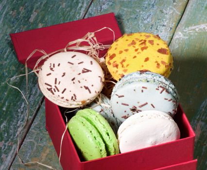 Assorted Traditional Colorful Macarons in Red Gift Box closeup on Green Cracked Wooden background