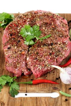 Marinated Raw Boneless Beef Shank with Herbs and Spices, Garlic and Chili Pepper closeup on Wooden Cutting Board on Cross Section on White background