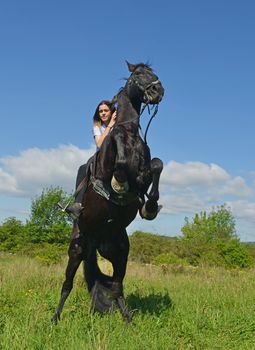 young riding girl and her black stallion in nature