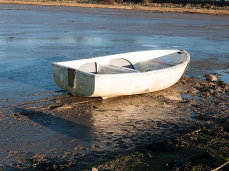 a boat standing stationary in the in mud with the tide out