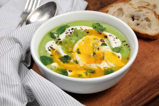 Pea puree soup with poached egg, sour cream, mint leaves seasoned with spices.