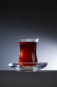 Cup of Turkish tea on saucer against nice dark background