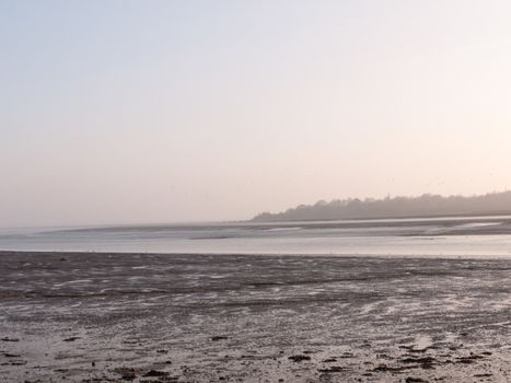 Various shots of the river and the mud, along with many birds, buoys, and other sea structures, as the sun sets