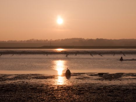 Various shots of the river and the mud, along with many birds, buoys, and other sea structures, as the sun sets