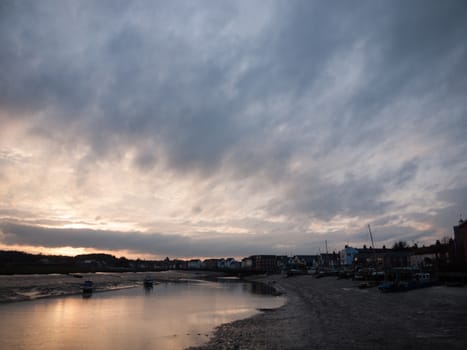 Low tide river with boats, a pier and more