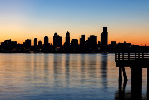 Seattle Washington city skyline silhouette from the pier at Alki Beach during orange glow sunrise 