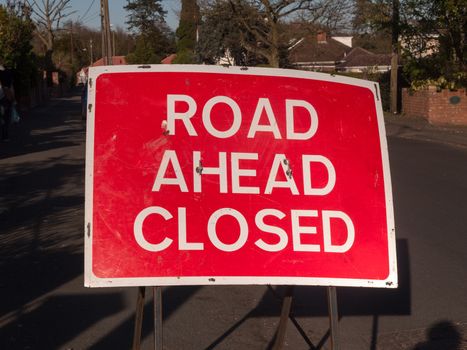 A a big red and white road closed ahead sign