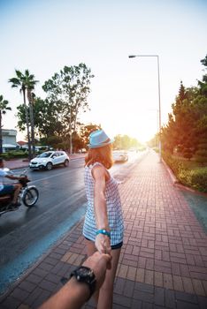 Beauty woman in blue hat holding man by hand and going around the Alanya city in Turkey