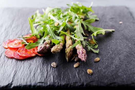 Fresh vegetables with slices of chorizo on a stone plate