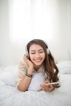 Woman Relaxing in bed and listening to music, relaxing in her living room