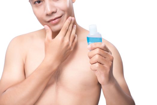 Confident man applying lotion after shave on face over white background.