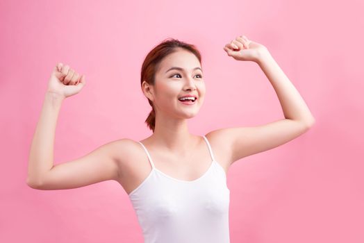 Portrait of a carefree young asian woman smiling with arms raised