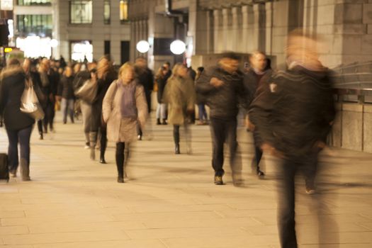 Commuters walking along London Bridge at night, London, England.