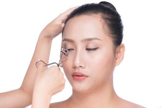 Make-up artist curling eyelash for asian model.
