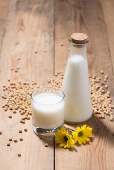 Soy milk or soya milk and soy beans in spoon on wooden table. 