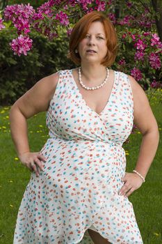 overweight woman wearing a summer dress, under a cherry tree