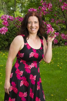 forty something woman wearing a summer dress, smelling cherry blossoms