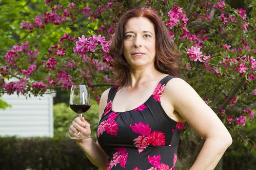 Woman in her forties wearing a summer dress, having a glass of red wine