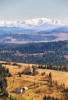 Snow caped mountains in sunny spring day. Beskids mountain range. Woods and meadows in a spring valley.