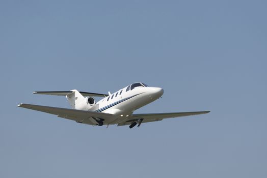 Business Jet directly after takeoff accelerating with withdrawing landing gear
