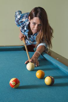 twenty something beautiful girl wearing a low cut plaid shirt about to shoot pool