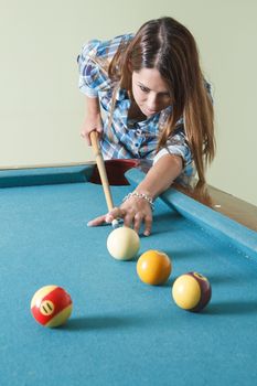 young woman wearing a low cut plaid shirt, playing pool