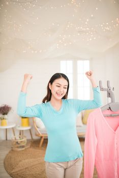 Happy young asian woman finish steaming clothes in room