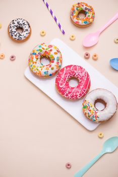 Party. Different colourful sugary round glazed donuts and bottles of drinks on light color background.
