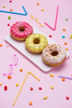 Party. Different colourful sugary round glazed donuts and bottles of drinks on pink background.