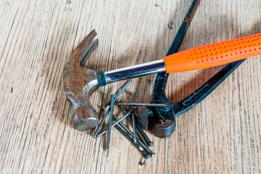 Black  mites and hammer with a red hand and several nails lie on a wooden board