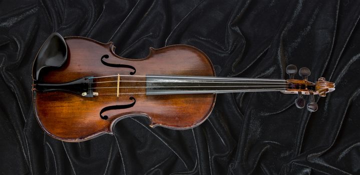 Old violin photographed against a black background relief