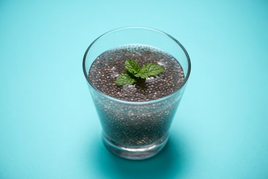 Glass of water with cup of healthy chia seeds and spoon. Text space.