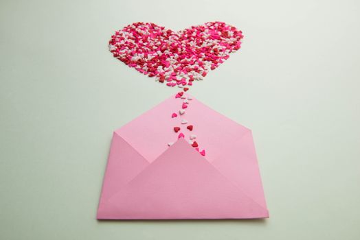 Sweets sugar candy hearts on envelope over green background