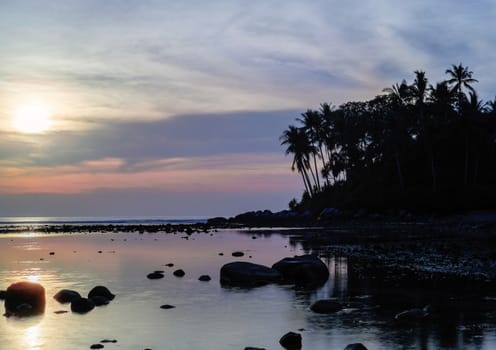 Beautiful colorful sunset near the smal eaxotic island with palms