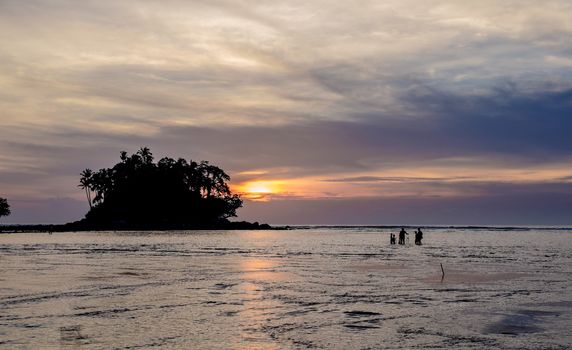 Fisherman with his family is checking nets in the beautiful sunset near tropical island. Phuket. Thailand