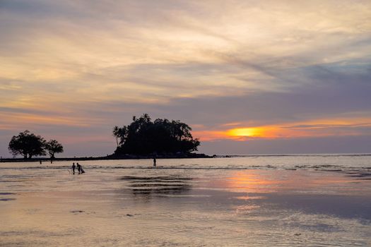 Fisherman with his family is checking nets in the beautiful sunset near tropical island. Phuket. Thailand