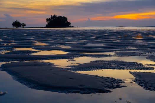 Beautiful colorful sunset near the small exotic island with palms